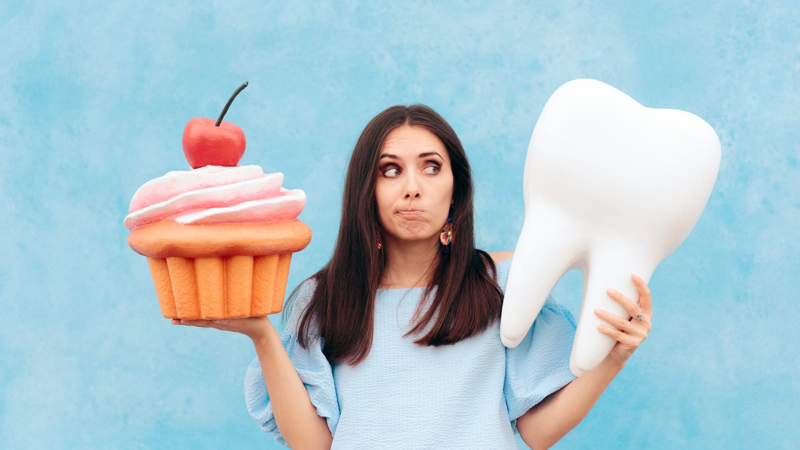 SIlly woman holding tooth and cupcake