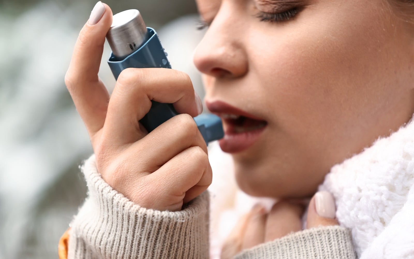 Young woman using asthma inhaler